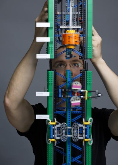 Mann setzt ein Modell eines Faserziehturms aus Legosteinen zusammen