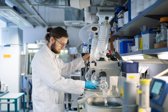 Wissenschaftler in einem Labor mit diversen, durch Glasrohre verbundenen Kolben und Geräten