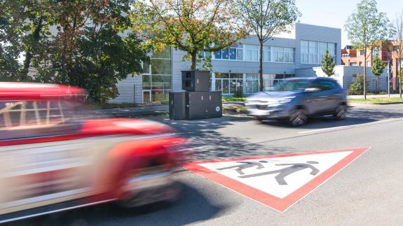 Zwei Autos fahren auf einer Straße an einem Blitzer vorbei