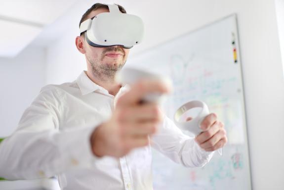 Ein Kollege bedient mir VR-Brille und Handles den avatera-Operationsroboter.
