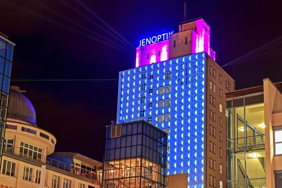 Blau beleuchtete Fassade des Ernst-Abbe-Hochhauses mit Jenoptik-Schriftzug auf dem Dach