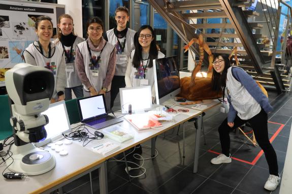 Ein junges Team von Forschenden an einem Infostand über Ameisen