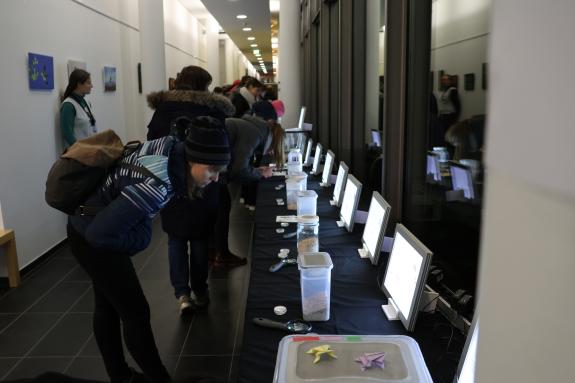 Besucherinnen und Besucher vor Behältern und leuchtenden Bildschirmen