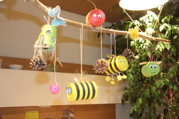 An einer Stange hänge Konservendosen, die als Bienen dekoriert wurden.