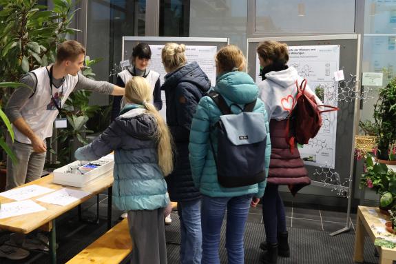 Forschende erklären einer Gruppe von Besucher*innen, welche Moleküle Pflanzen bilden können.