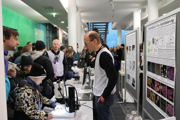 Wissenschaftler und Besucher*innen an einem Infostand.
