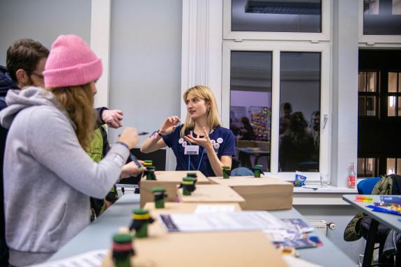 M.Sc. Sarah Weißhart, wissenschaftliche Mitarbeiterin am Lehrstuhl für Klinische Psychologie, spricht mit Besucher:innen über das Mitmachangebot „Multimodales Memory“.