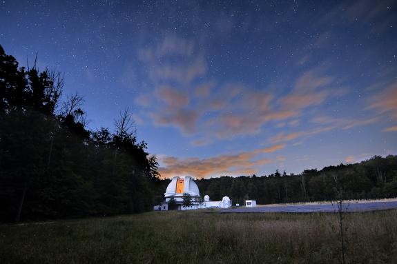 Blick auf die offene Kuppel der Thüringer Landessternwarte bei Nacht mit dem LOFAR-Radioteleskop und dem Tautenburger Sonnenlabor.