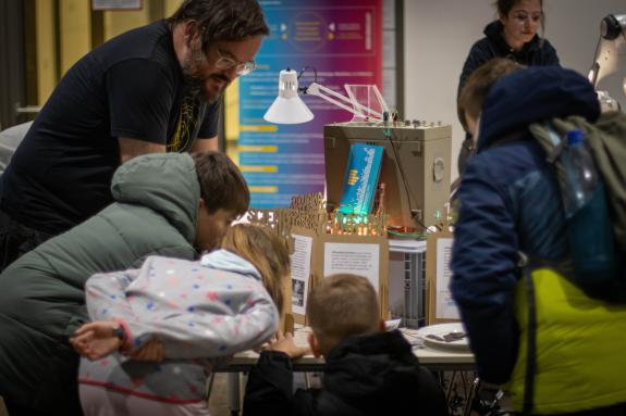 Kinder beugen sich über den Arbeitstich der Lichtwerkstatt