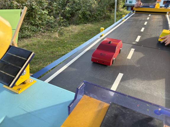 Spielzeug-Elektro-Autofährt auf einer Straße mit PV-Ladestatione